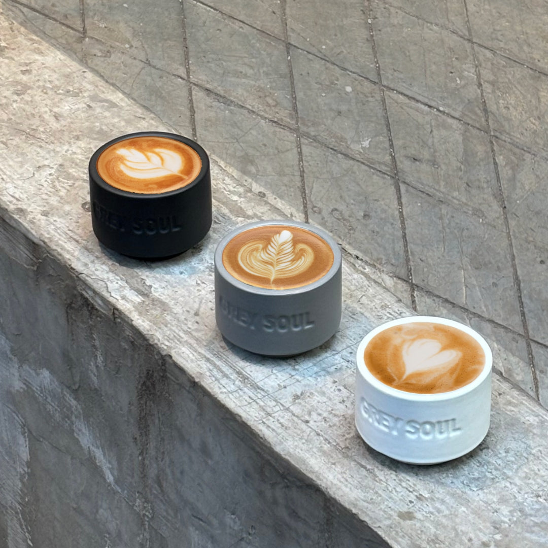 Three coffee cups with latte art on a stone ledge, branded cups by grey soul coffee roasters