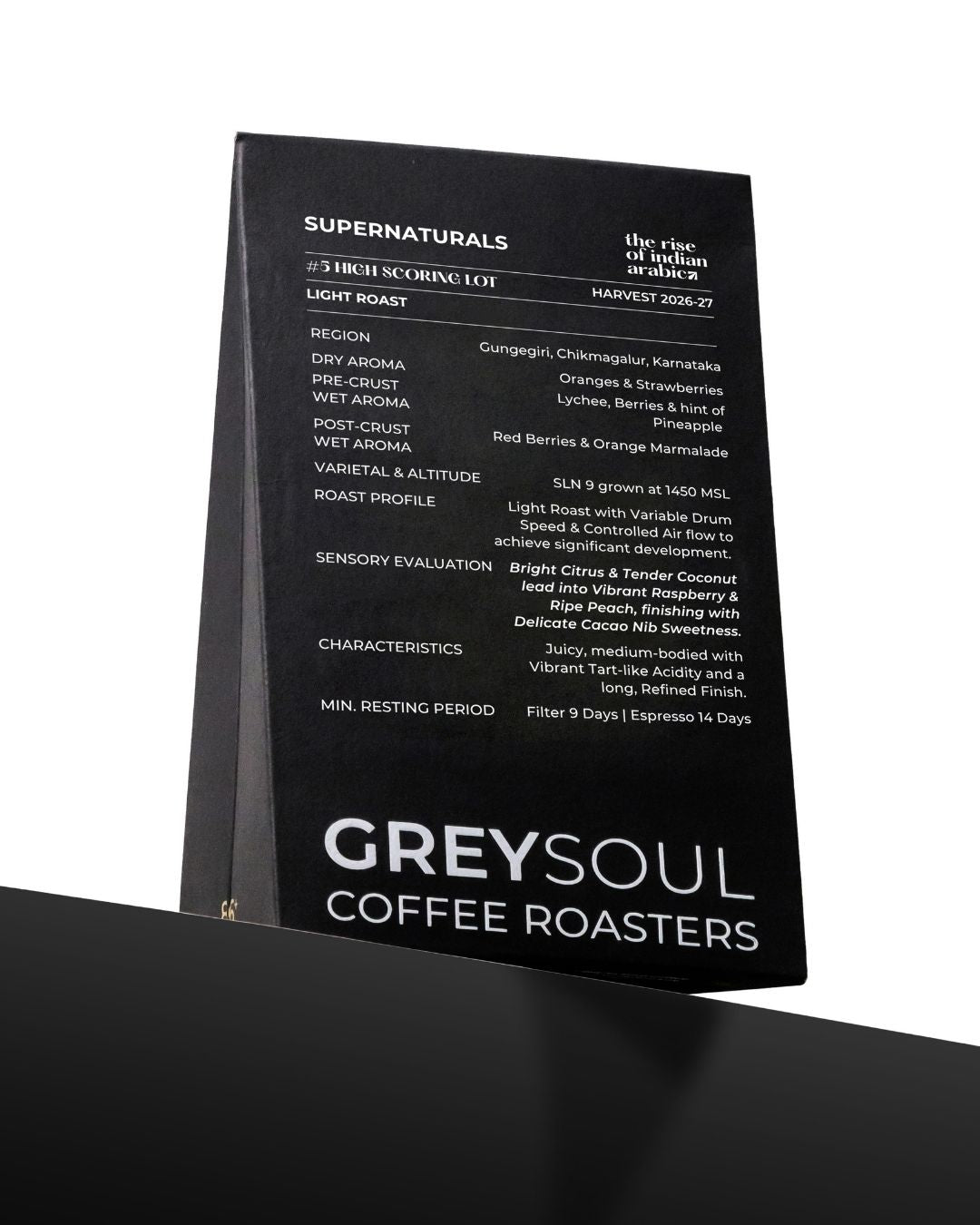 A black coffee roaster information card or label for Greysoul Coffee Roasters, featuring white text detailing the Supernaturals blend, roast details, and sensory evaluation, shown standing on a black surface against a white background.